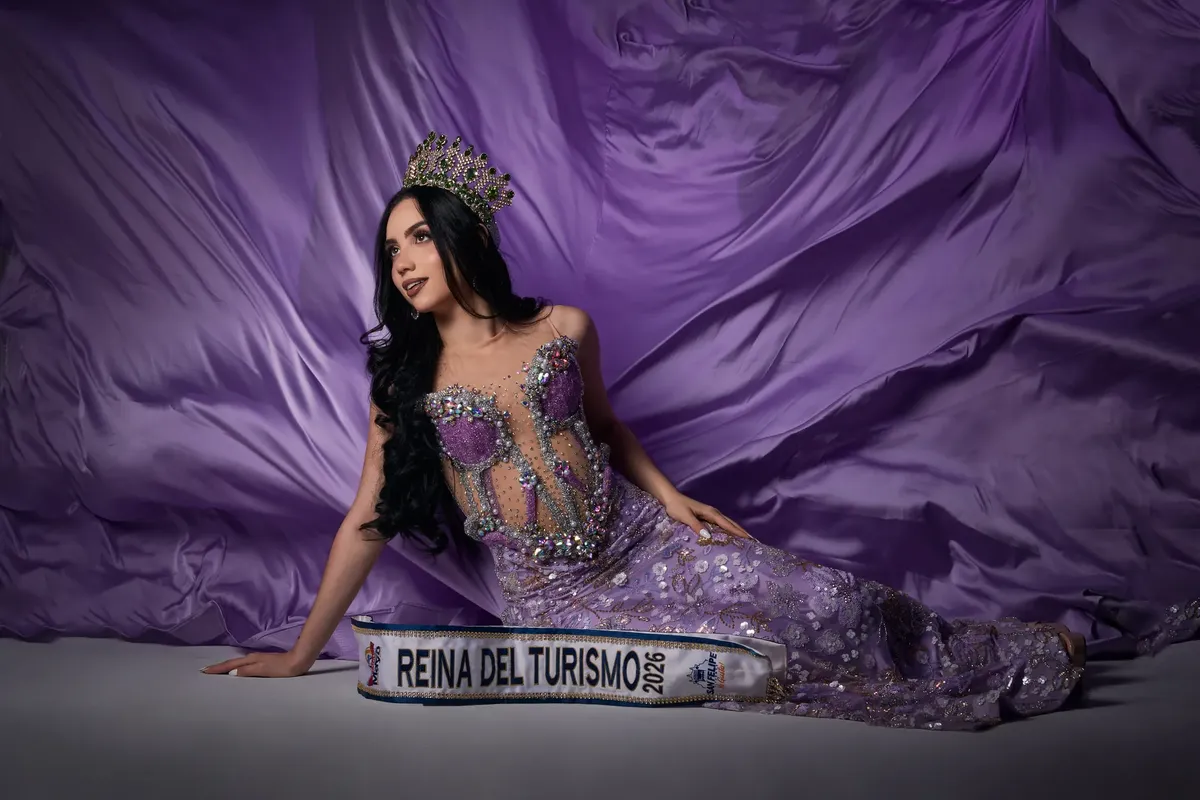 Pageant winner in ornate purple gown with crown, posing elegantly.