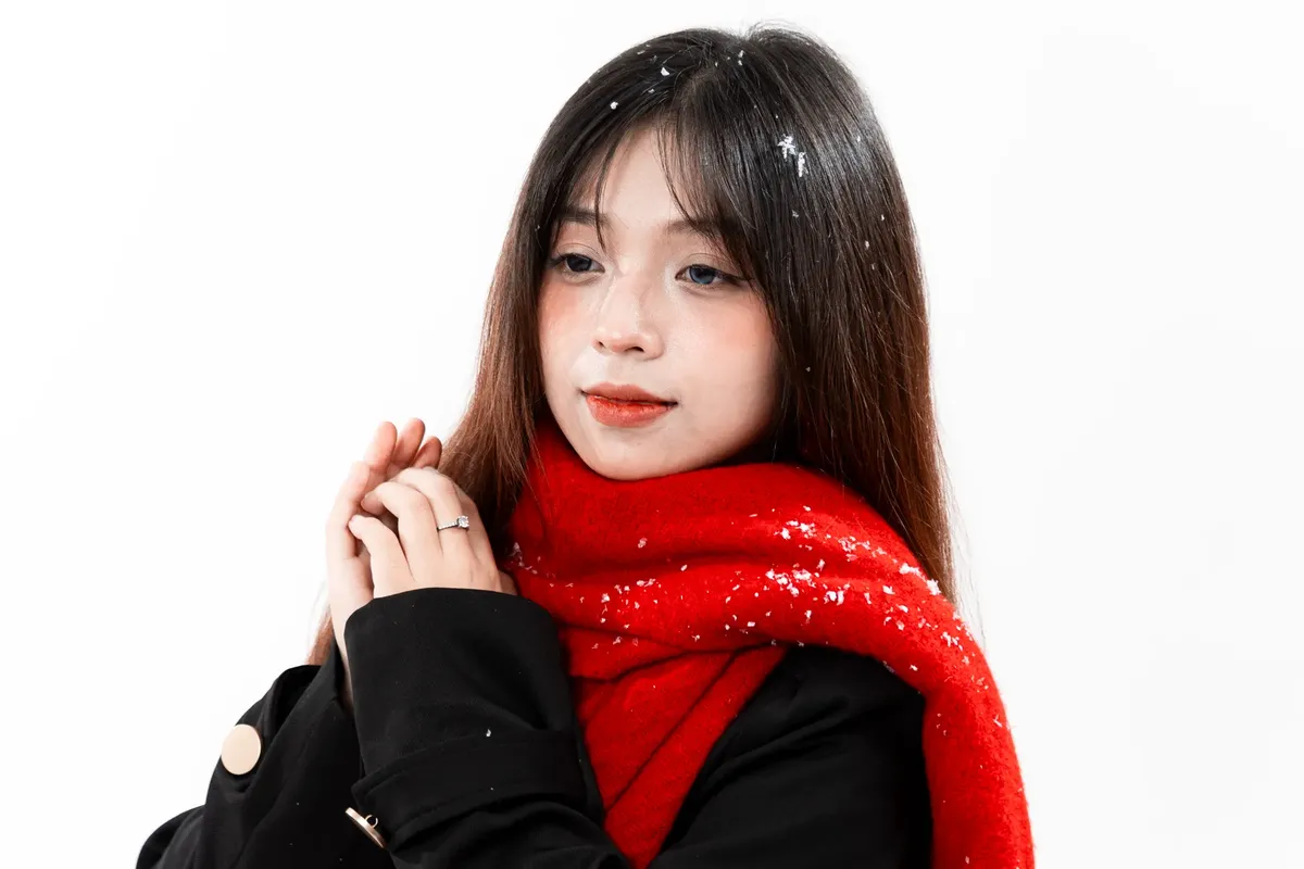 紅いスカーフと黒いコートを着た若婦人が雪の冬の設定の中でいます