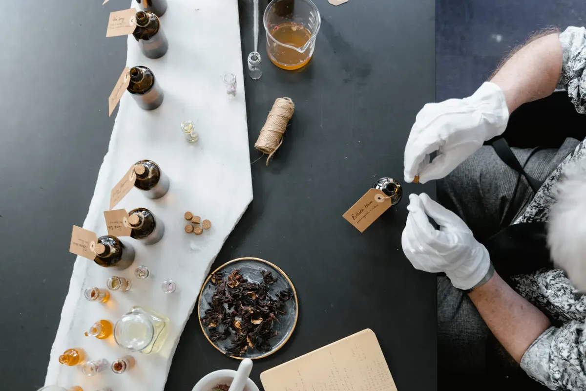 香料製造工場のオーバーヘッドビュー、手袋、ガラスのボトル、そして自然な原料が見える